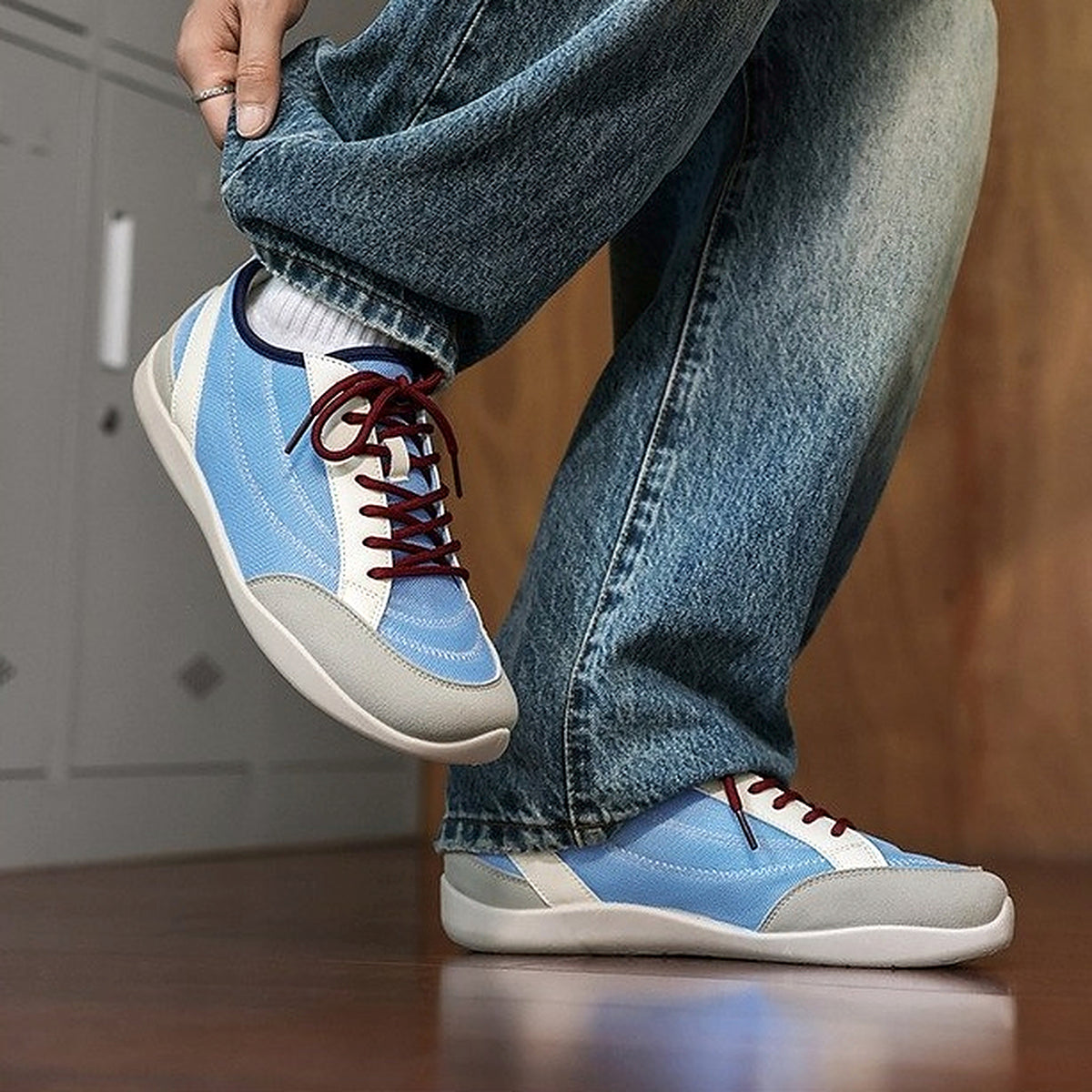 SNK AeroStitch Trainer Sky Blue on feet, leg raised with denim